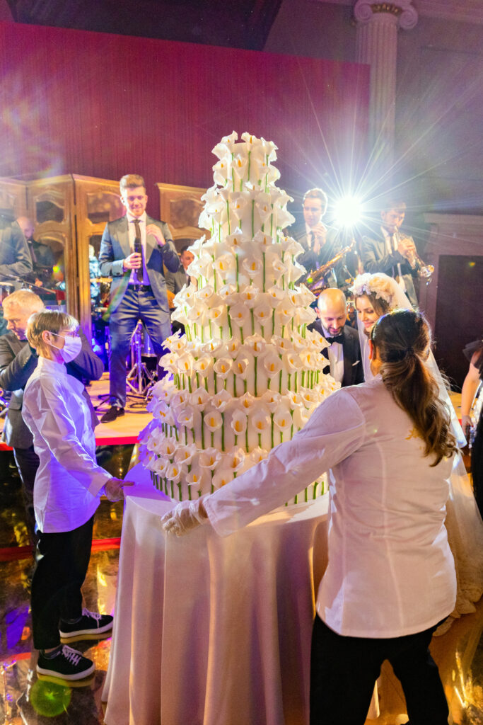 Yevnig Davis from ByYevnig wheels a huge cake into position at The Banqueting House London, for the bride and groom to cut.