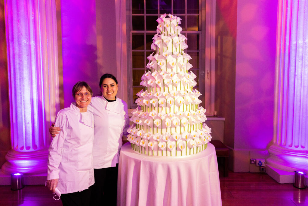 Yevnig Davis, creative director and master baker with Chris, baker and general assistant at By Yevnig standing next to their huge contemporary wedding wedding cake creation at The Banqueting House, London.