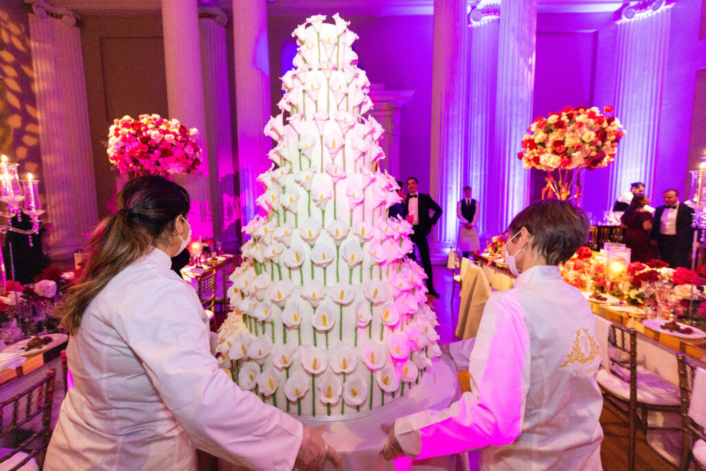 Yevnig Davis and Chris from By Yevnig wheel a statement contemporary floral wedding cake into position.