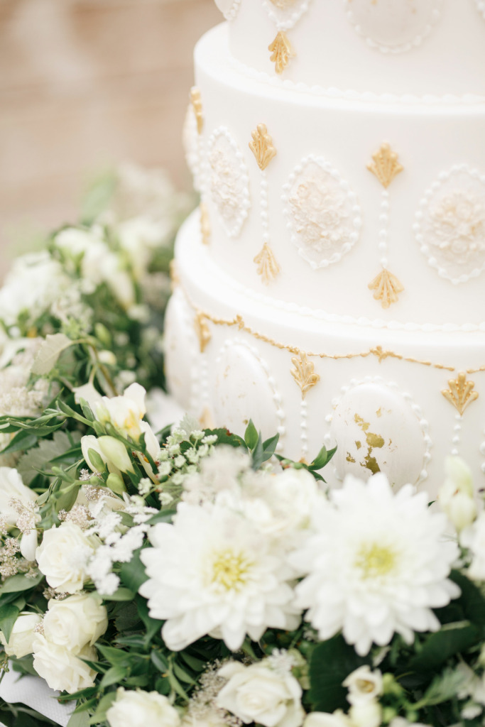 Close up of By Yevnig luxury wedding cake in ivory white and gold with fresh florals by Emma Soulsby
