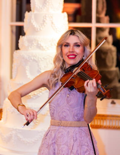 Violinst stands in front of luxury wedding cake By Yevnig