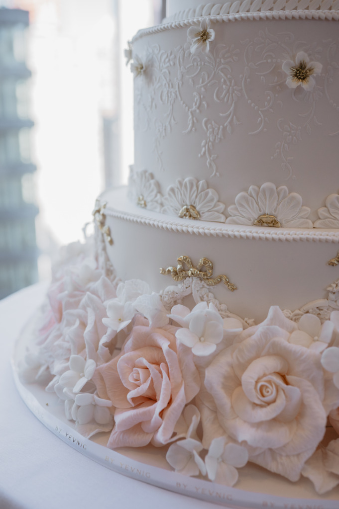 Close-up photograph of luxury wedding cake, By Yevnig at the Mandarin Oriental New York, showing detail hand-crafted sugar roses, and piped decorations