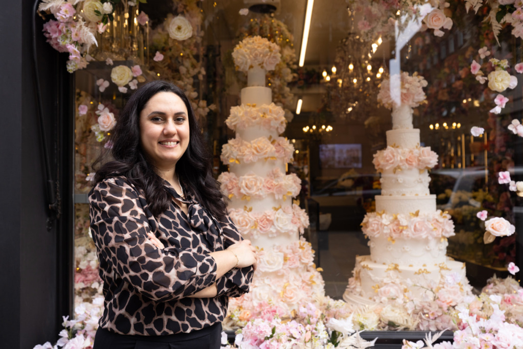 Yevnig stands beside the Neill Strain Floral Couture window, Mayfair London with two luxury By Yevnig floral wedding cakes surrounded with a fresh floral installation.